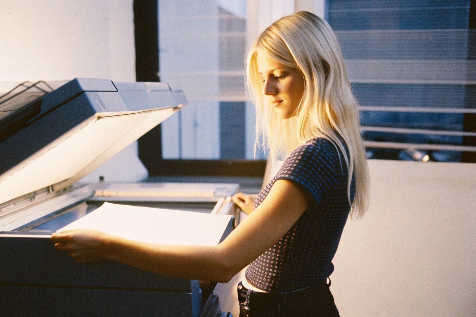 A designer copying a stack of printed files in an office